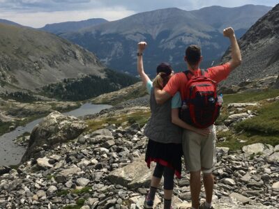 Couple standing with arms raised climbing mountains together